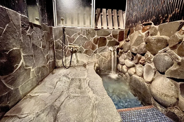 石造りの浴槽と岩の壁に囲まれた露天風の貸切風呂