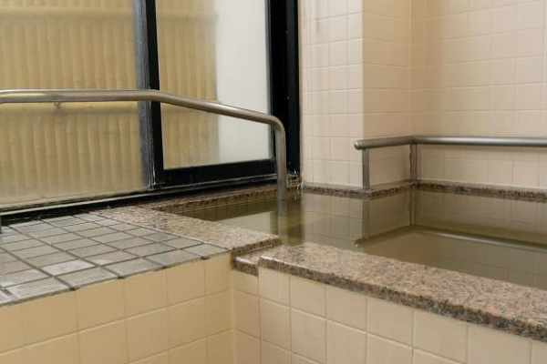 シンプルで落ち着いた雰囲気のタイル風呂と手すり付きの湯舟