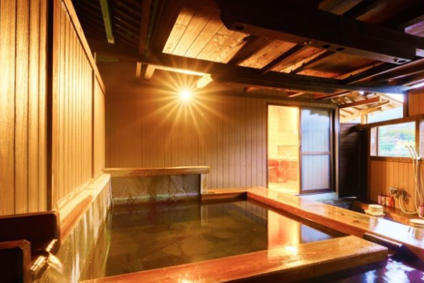 灯りに照らされた岩風呂の貸切露天。木と竹が織りなす趣ある空間